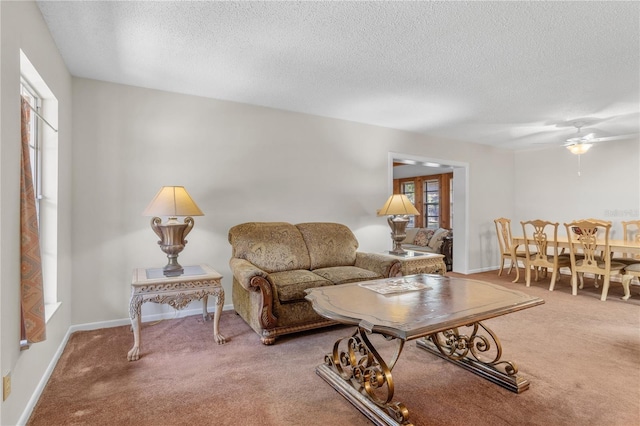 carpeted living room featuring ceiling fan and a textured ceiling