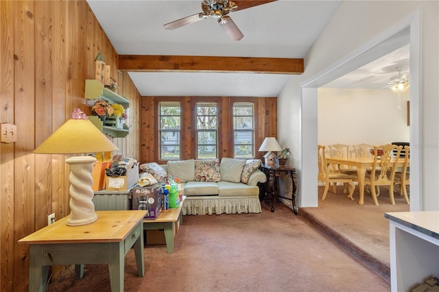 living area featuring carpet flooring, lofted ceiling with beams, ceiling fan, and wooden walls