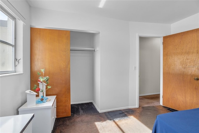 bedroom featuring dark colored carpet, a closet, and multiple windows