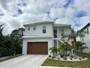 view of front facade with metal roof, concrete driveway, an attached garage, and a front yard