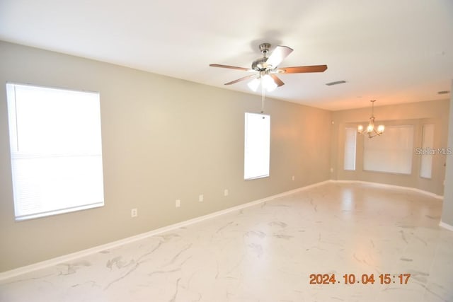 spare room with ceiling fan with notable chandelier