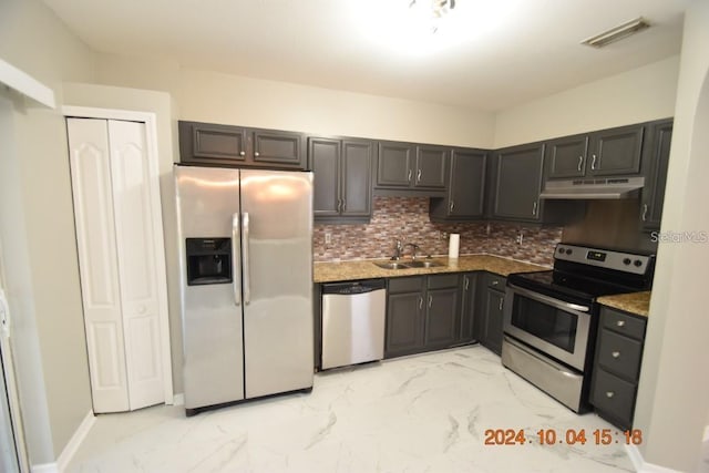 kitchen with appliances with stainless steel finishes, tasteful backsplash, dark brown cabinets, sink, and stone counters