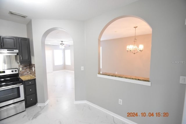 kitchen featuring decorative backsplash, light stone counters, ceiling fan with notable chandelier, stainless steel electric stove, and decorative light fixtures