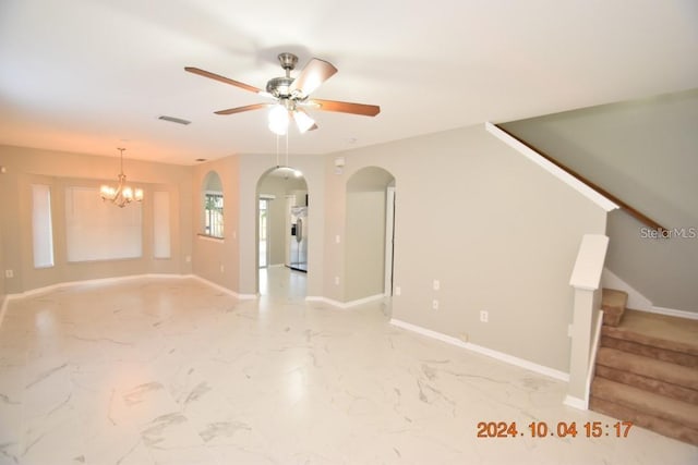 unfurnished living room featuring ceiling fan with notable chandelier