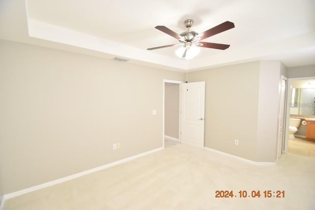 unfurnished bedroom with connected bathroom, ceiling fan, and light colored carpet