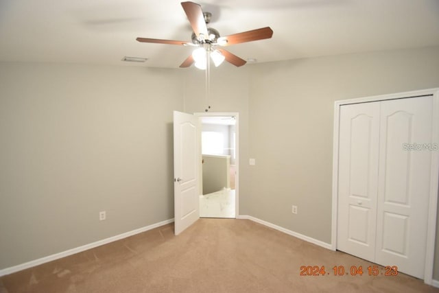 unfurnished bedroom featuring ceiling fan, light carpet, and a closet