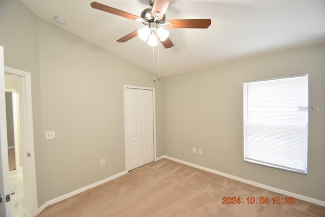 carpeted spare room with ceiling fan and lofted ceiling