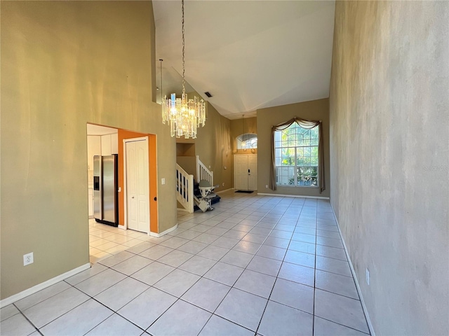 interior space with pendant lighting, light tile patterned floors, stainless steel fridge with ice dispenser, and high vaulted ceiling