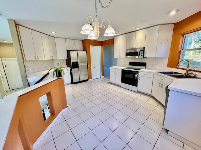 kitchen featuring pendant lighting, white cabinets, sink, appliances with stainless steel finishes, and a notable chandelier