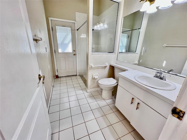 bathroom with toilet, a tile shower, vanity, and tile patterned floors