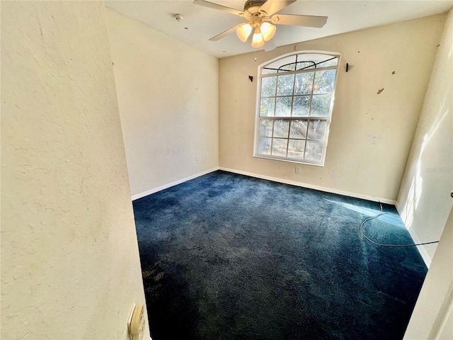 spare room with dark colored carpet and ceiling fan