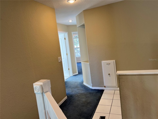 corridor with a textured ceiling and light tile patterned flooring