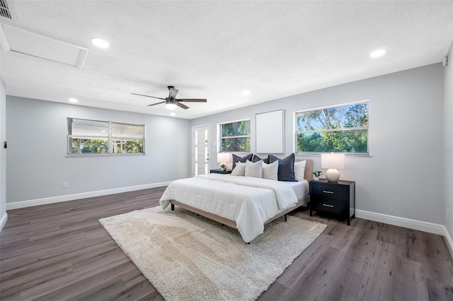 bedroom featuring a textured ceiling, ceiling fan, dark wood-type flooring, and multiple windows