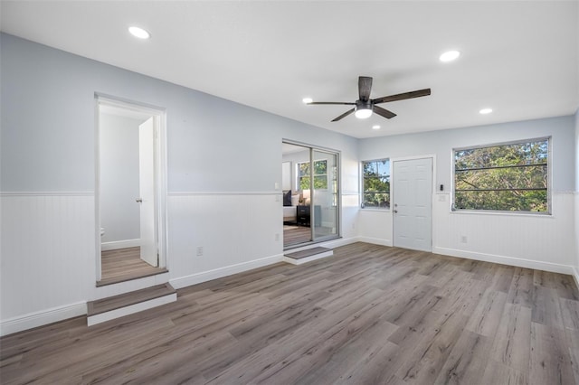 empty room with light hardwood / wood-style flooring, ceiling fan, and wood walls