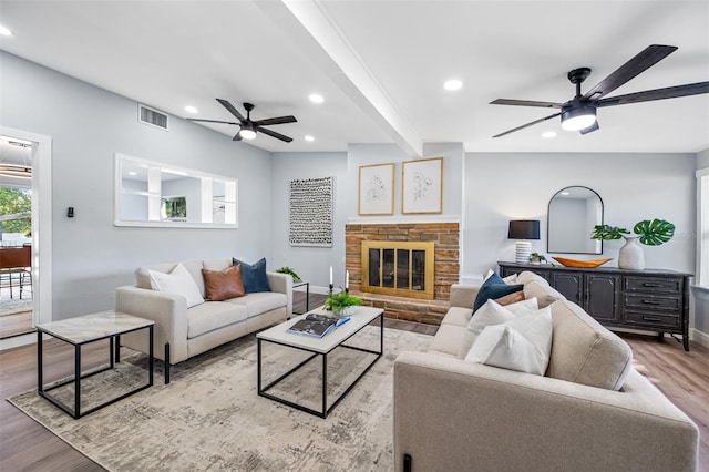 living room with a fireplace, beam ceiling, light hardwood / wood-style flooring, and ceiling fan