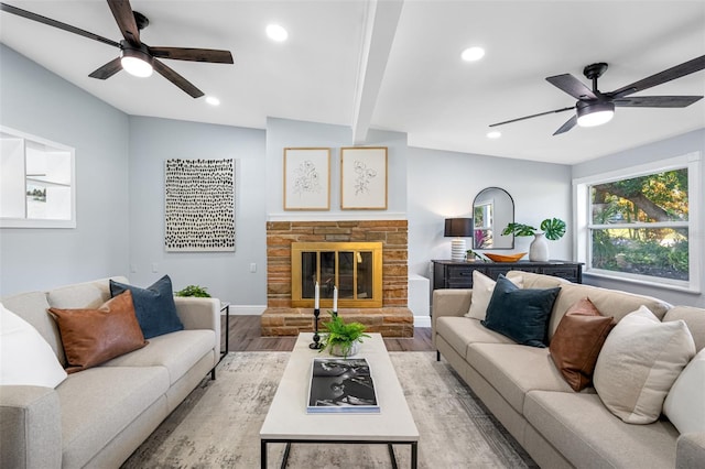 living room with lofted ceiling with beams, a stone fireplace, and light hardwood / wood-style flooring