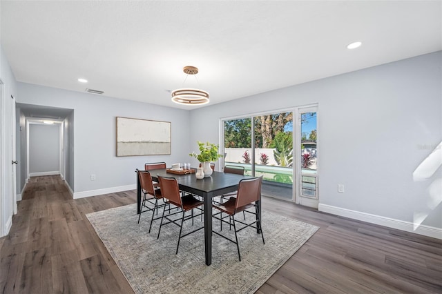 dining room with dark wood-type flooring and a notable chandelier