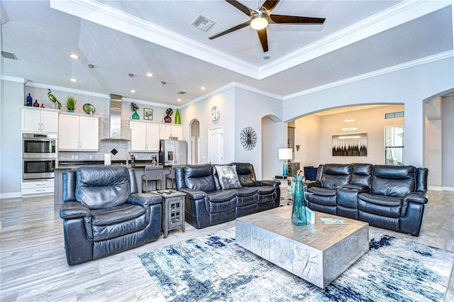 living room featuring crown molding, sink, ceiling fan, and light wood-type flooring