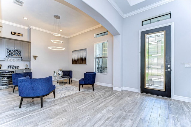 entrance foyer with bar, plenty of natural light, ornamental molding, and light wood-type flooring