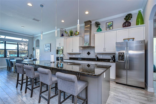 kitchen with a spacious island, white cabinetry, stainless steel appliances, and wall chimney range hood