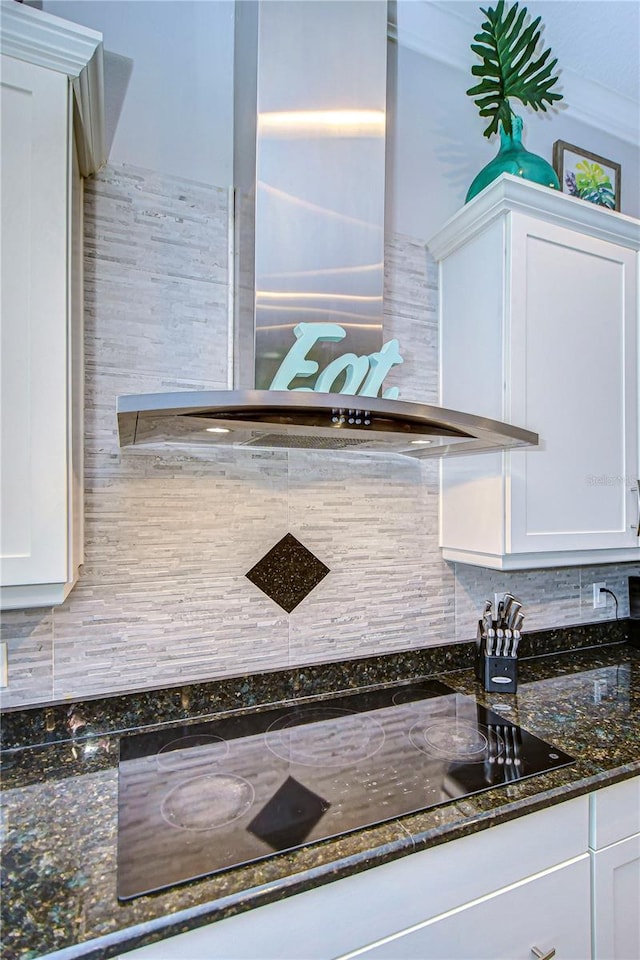 interior details with tasteful backsplash, white cabinets, and wall chimney exhaust hood