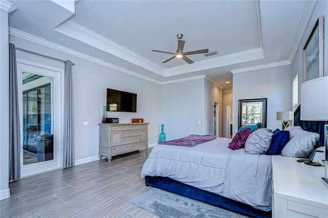 bedroom featuring ceiling fan, wood-type flooring, ornamental molding, and a tray ceiling