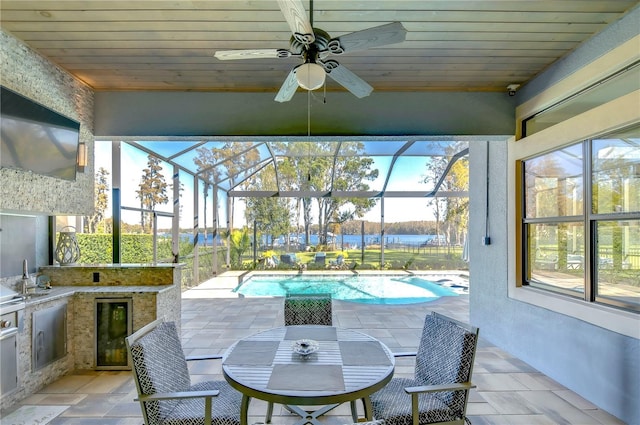 view of patio featuring ceiling fan, a lanai, exterior kitchen, and beverage cooler