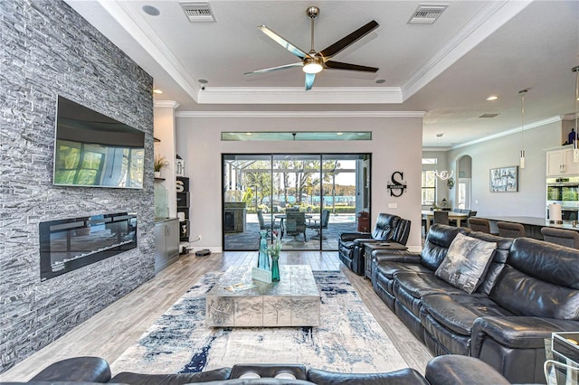 living room featuring a tray ceiling, light hardwood / wood-style flooring, ceiling fan, and ornamental molding