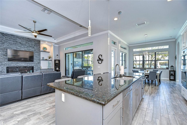 kitchen with dark stone counters, white cabinetry, sink, and pendant lighting