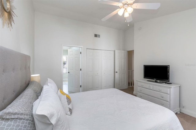 carpeted bedroom with ceiling fan, a closet, and a high ceiling