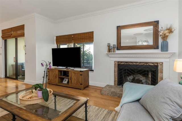 living room featuring a tile fireplace, crown molding, and light wood-type flooring