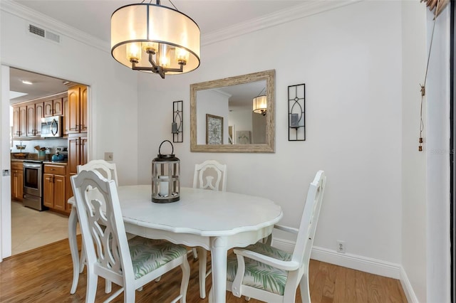 dining room featuring a chandelier, light hardwood / wood-style floors, and crown molding