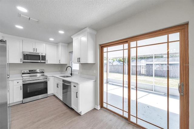 kitchen featuring white cabinets, appliances with stainless steel finishes, light hardwood / wood-style flooring, and sink