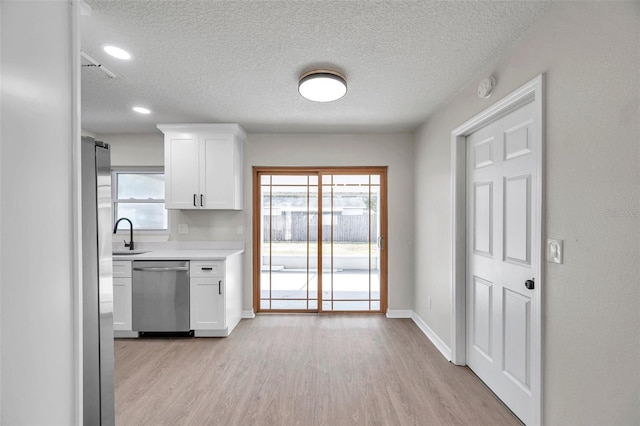 kitchen with dishwasher, a textured ceiling, white cabinets, and light hardwood / wood-style floors