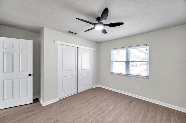 unfurnished bedroom featuring ceiling fan, light hardwood / wood-style floors, a textured ceiling, and a closet