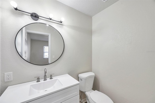 bathroom featuring vanity, a textured ceiling, and toilet