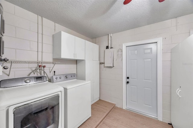 laundry area featuring cabinets, a textured ceiling, ceiling fan, washing machine and clothes dryer, and electric panel