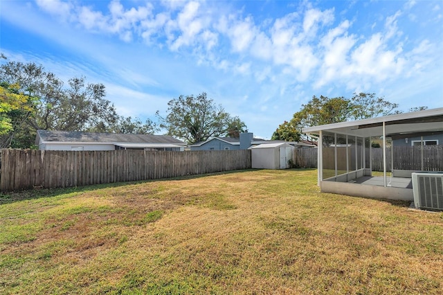 view of yard featuring a sunroom, a storage shed, and central air condition unit