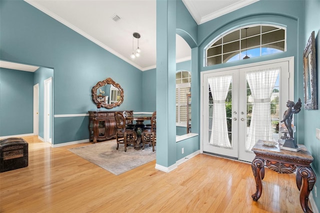 foyer featuring crown molding, french doors, a towering ceiling, and hardwood / wood-style floors