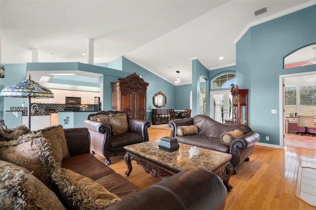 living room with vaulted ceiling, light hardwood / wood-style flooring, plenty of natural light, and crown molding