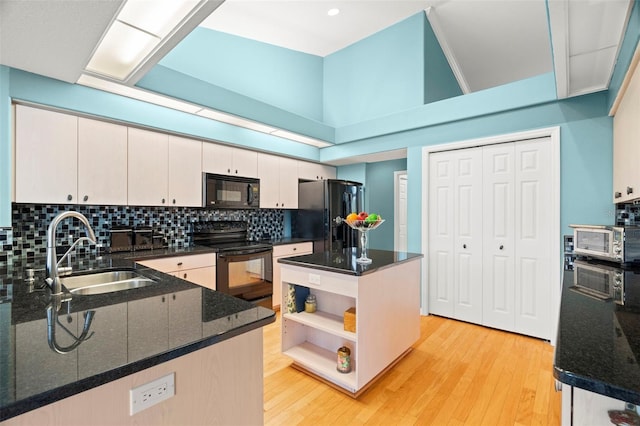 kitchen with black appliances, white cabinets, sink, tasteful backsplash, and light hardwood / wood-style floors