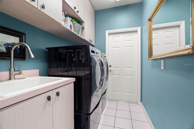 washroom with cabinets, a textured ceiling, sink, light tile patterned floors, and washing machine and clothes dryer