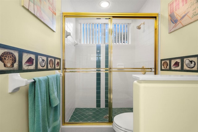 bathroom with toilet and a shower with door