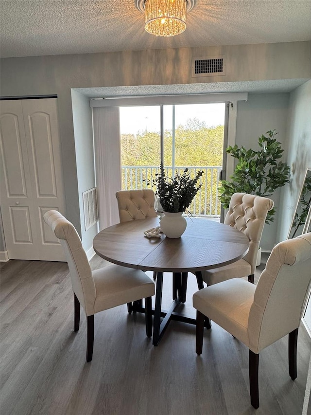 dining room featuring hardwood / wood-style floors, a chandelier, and a textured ceiling