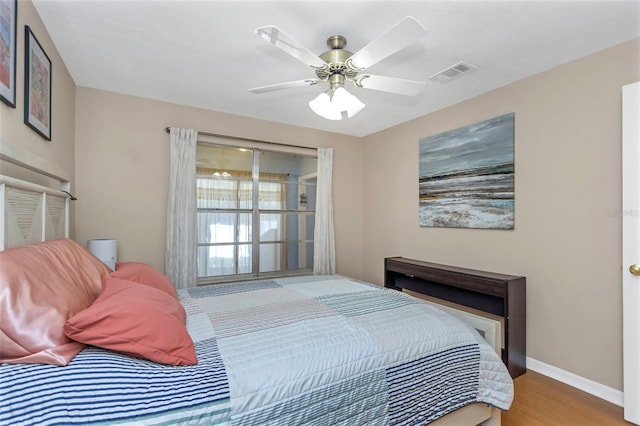 bedroom featuring visible vents, ceiling fan, baseboards, and wood finished floors