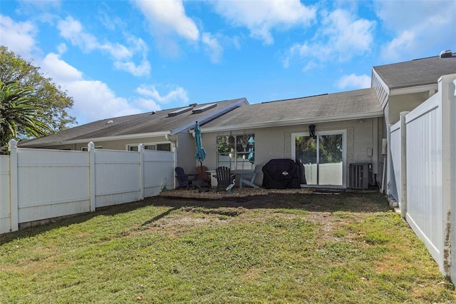 back of house featuring central AC unit, a yard, a fenced backyard, and stucco siding