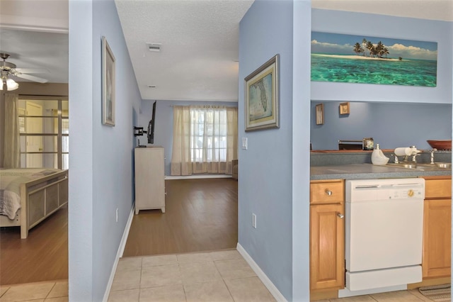 kitchen featuring a ceiling fan, a textured ceiling, light tile patterned flooring, white dishwasher, and baseboards