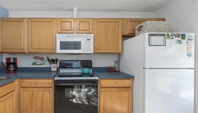 kitchen with tile patterned floors, white appliances, dark countertops, and a textured ceiling