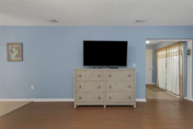 unfurnished living room with wood finished floors, visible vents, and a textured ceiling