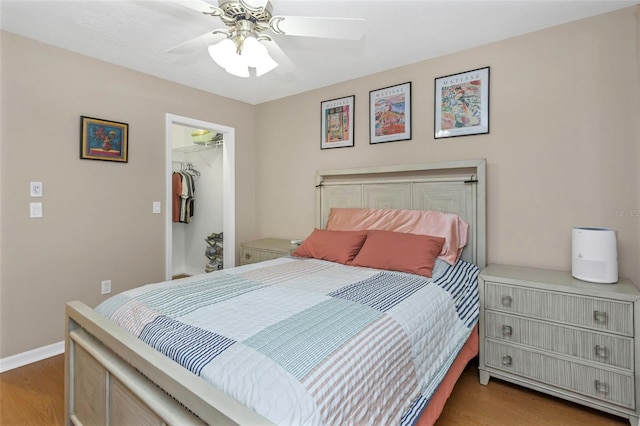 bedroom featuring a closet, a spacious closet, ceiling fan, and wood finished floors